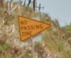 yellow triangle sign that says "no passing zone"